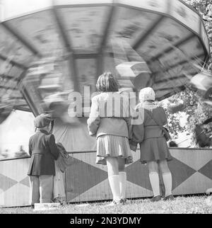Parc d'attractions dans le 1940s. Les enfants devant une tournée de joyeux-tours apparemment fascinés par l'attraction mouvante. Suède 1948 Kristoffersson réf. AR44-3 Banque D'Images