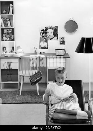 Dans le 1960s. Une adolescente dans sa chambre typique de 1960s, un bureau et ses choses avec des photos d'idoles du mur Audrey Hepburn et Elvis Presley. Suède 1960 Banque D'Images