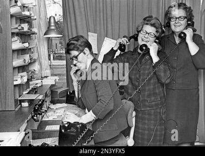 Dans le 1960s. Trois femmes s'amusant au travail, tenant plusieurs téléphones et riant. Suède 1967 Banque D'Images