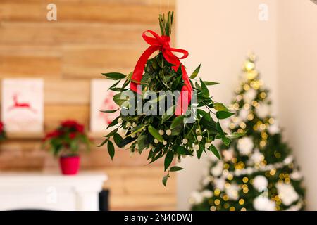 Bouquet de GUI avec noeud rouge suspendu dans la chambre décorée pour Noël Banque D'Images