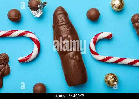 Composition de la couche plate avec bonbons et bonbons au Père Noël au chocolat sur fond bleu clair Banque D'Images