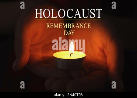 Journée internationale de commémoration de l'Holocauste. Femme tenant une bougie allumée dans l'obscurité, gros plan Banque D'Images