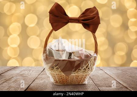 Panier en osier rempli de produits cosmétiques sur la table contre des lumières de fête floues Banque D'Images