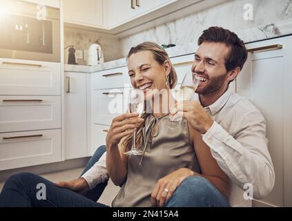 Rire, amour et couple avec du champagne dans la cuisine pour la fête, anniversaire et Saint Valentin. Comique, relax et drôle homme et femme de boire Banque D'Images