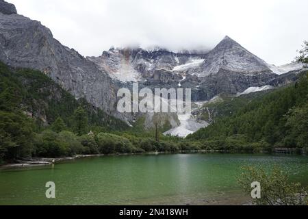 Un lac et des montagnes couvertes de nuages dans le parc national de Daocheng Yading, Sichuan, Chine. Banque D'Images