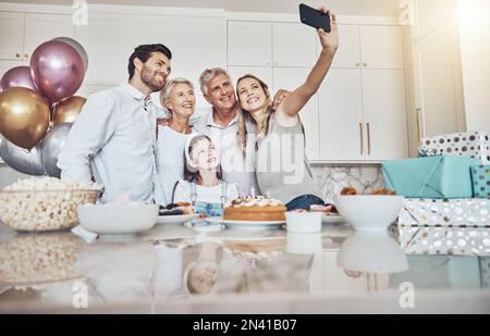 Fête d'anniversaire, gâteau et selfie de famille dans la cuisine pour un souvenir heureux, les médias sociaux ou la photo de profil. Amour, nourriture et fille, mère et grands-parents Banque D'Images