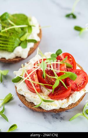 Pain grillé avec fromage à la crème, tomates cerises et micro verts. Concept de petit déjeuner sain. Banque D'Images