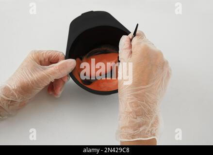 Femme préparant le colorant capillaire dans un bol à la table blanche, gros plan Banque D'Images