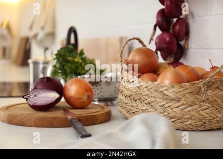 Des oignons frais coupés et entiers sur le comptoir dans la cuisine moderne Banque D'Images