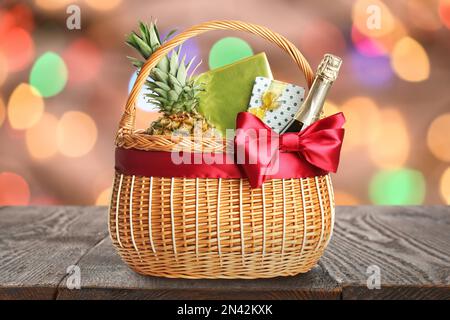 Panier en osier rempli de cadeaux sur une table en bois contre des lumières de fête floues Banque D'Images