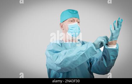 Médecin spécialiste des maladies infectieuses dans des combinaisons de protection et un masque met des gants de protection. Banque D'Images