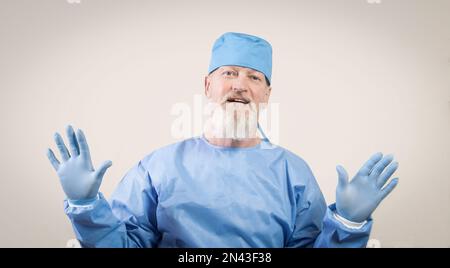 Le médecin en protection bleue des maladies infectieuses montre les mains dans des gants de protection en caoutchouc. Banque D'Images
