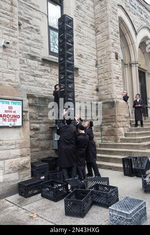 Les étudiants yeshiva juifs ultra-orthodoxes d'une école urbaine construisent une tour à partir de caisses à lait pendant leur récréation. À New York. Banque D'Images