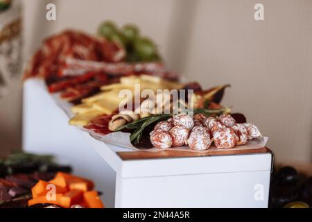 Table de hors-d'œuvre avec viande et fromage. Salami, saucisses, fromage, raisins, tomates, olives vertes, romarin, tapas sur assiettes en bois. En-cas Banque D'Images