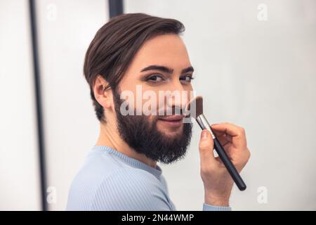 Transgenre personne appliquant de la poudre sur le visage Banque D'Images