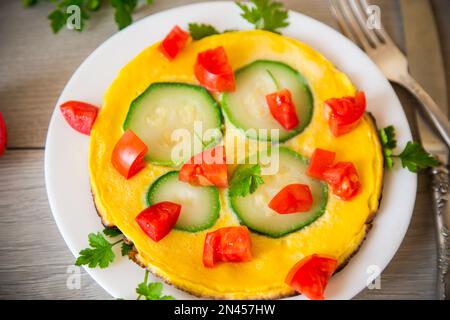 Omelette frite avec courgettes, tomates, herbes dans une assiette Banque D'Images