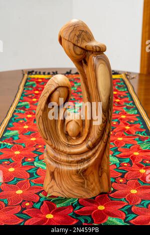 Une sculpture en bois d'olive de Marie, Joseph et Jésus sur une table de pointettia dans une maison aux États-Unis. Le coureur de table est de Oaxaca, Mexique Banque D'Images