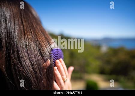 Belle fille brossant les cheveux, modèle coiffant les cheveux noirs se préparer à aller à un événement en australie Banque D'Images