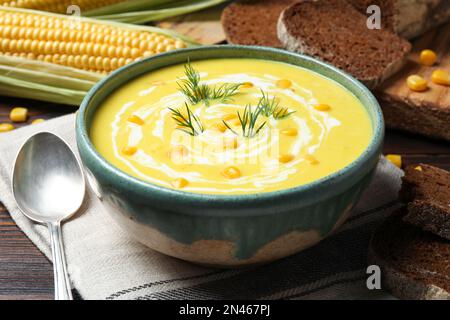 Délicieuse soupe crémeuse de maïs servie sur une table en bois Banque D'Images