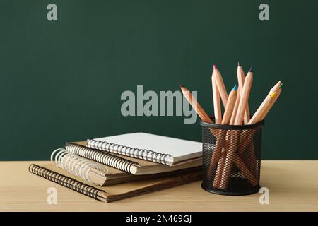 Différentes fournitures scolaires sur une table en bois près du tableau noir vert. Retour à l'école Banque D'Images