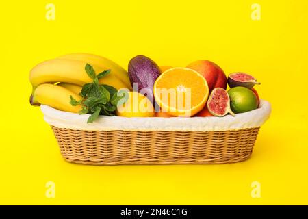 Assortiment de fruits exotiques frais dans un panier sur fond jaune Banque D'Images