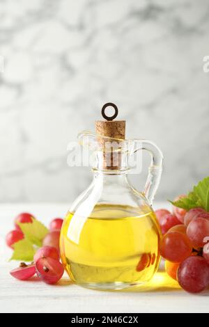 Huile de pépins de raisin naturel et baies fraîches sur table en bois blanc. Cosmétique biologique Banque D'Images