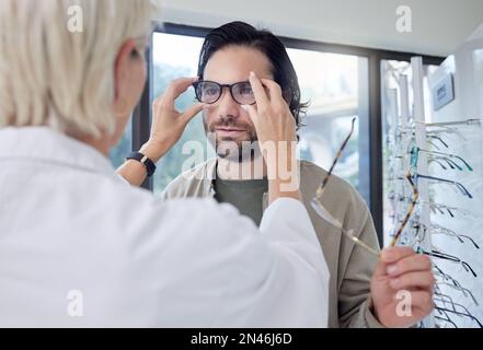 Optométriste, lunettes et homme en magasin pour le choix des cadres, de la vue et de la vision. Le visage du client, les nouveaux lunettes et le test de soin des yeux pour la prescription Banque D'Images