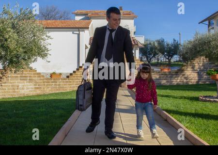 Image d'un homme d'affaires élégant revenant du travail sur son allée tenant la main d'une adorable petite fille. Amour et acceptation de la fille Banque D'Images
