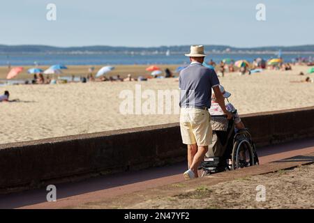 homme marchant sa vie dans un fauteuil roulant près de la plage Banque D'Images