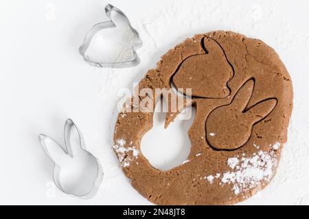 Pâte de pain d'épice de pâques crue avec des couteaux et de la farine. Préparation de biscuits de Pâques. Arrière-plan blanc. Vue de dessus Banque D'Images