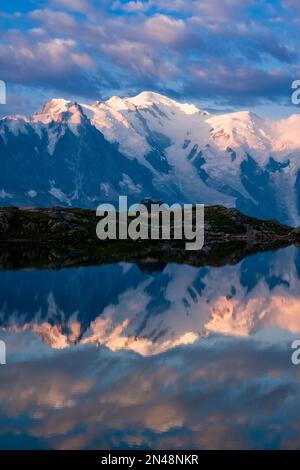 Les sommets du massif du Mont blanc et quelques nuages, qui réfléchissent au lever du soleil sur la surface des Lacs des Chéserys, une tente installée sur une crête. Banque D'Images