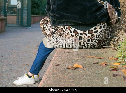 vue arrière d'une femme avec un pantalon à pois à imprimé léopard assis à l'extérieur Banque D'Images