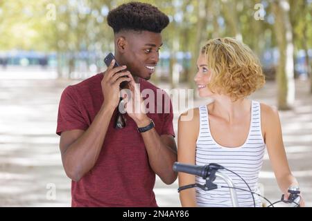 jeune couple multiracial avec vélo debout dans le parc Banque D'Images
