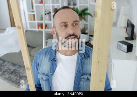 homme d'âge moyen tenant du bois à l'intérieur Banque D'Images