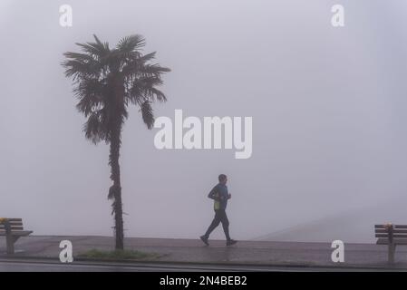 Jogger sur un froid, brumeux matin gelé courant le long du front de mer à Southend sur la mer, Essex, Royaume-Uni Banque D'Images