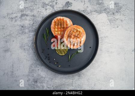 Rouleau de saumon grillé avec mozzarella. Décoration avec vert citron vert et fleurs comestibles Banque D'Images