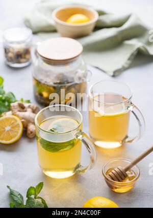 Deux verres de thé au citron frais, au miel, à la menthe et au gingembre sur un fond clair avec théière et lumière du matin en gros plan. Le concept d'un Dri sain Banque D'Images