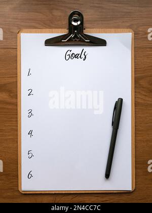 Vue de dessus du presse-papiers, du stylo et du papier écrit avec des chiffres et des objectifs. Banque D'Images