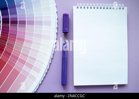 Échantillons de peinture, nuance multi-couleurs pour la conception. Arrière-plan lilas, bloc-notes, marqueur violet. Copier l'espace. Banque D'Images