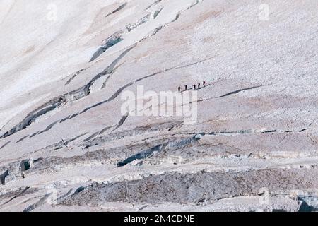 Vue aérienne des alpinistes traversant la partie supérieure du glacier géant avec des pistes et de grandes crevasses. Banque D'Images