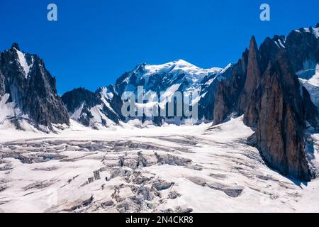 Vue sur les pistes et les crevasses de la partie supérieure du glacier géant, le sommet du Mont blanc au loin. Banque D'Images