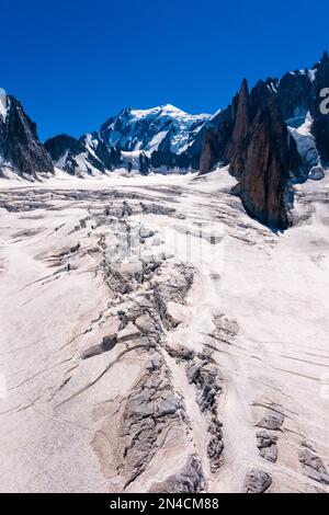 Vue sur les pistes et les crevasses de la partie supérieure du glacier géant, le sommet du Mont blanc au loin. Banque D'Images
