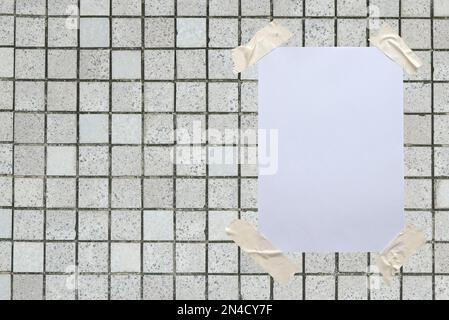 Papier blanc vierge fixé au mur avec du ruban adhésif. Banque D'Images