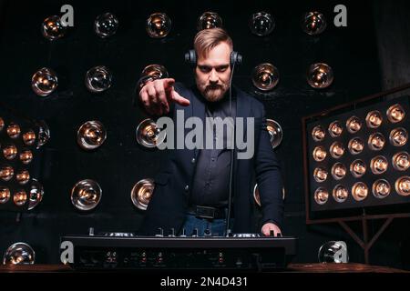 Un DJ barbu joue de la musique lors d'une fête en club Banque D'Images