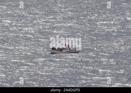 Les migrants algériens de sexe masculin brandirent des gilets de sauvetage pour attirer l'attention, ayant perdu de l'énergie sur leur bateau alors qu'il dévie dans la mer Méditerranée, août 2022. Banque D'Images