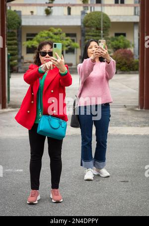 Deux femmes vietnamiennes touristes prennent des selfies à Mong Cai, Vietnam, à la frontière avec la Chine. Banque D'Images