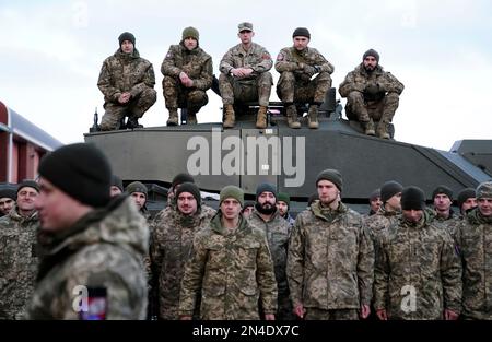 Les soldats se réunissent alors que le président ukrainien Volodymyr Zelensky et le Premier ministre Rishi Sunak rencontrent des troupes ukrainiennes formées pour commander les chars Challenger 2 dans un site militaire de Lulworth, Dorset, lors de sa première visite au Royaume-Uni depuis l'invasion russe de l'Ukraine. Date de la photo: Mercredi 8 février 2023. Banque D'Images