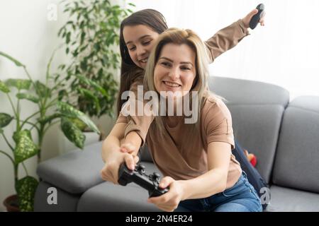 Mère et fille jouant à des jeux vidéo sur ordinateur portable à la maison. Banque D'Images