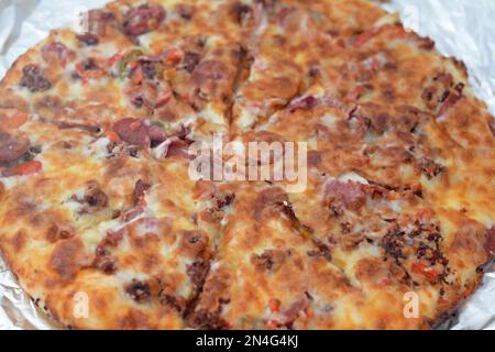 Pizza italienne avec morceaux de pastrami, viande, boeuf et salami, avec fromage mozzarella et poivrons, pizza cuite avec ketchup prête à être servi comme lun Banque D'Images