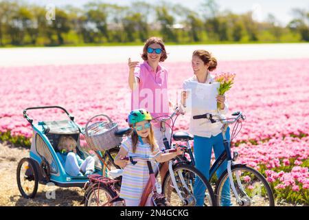 Heureux famille néerlandaise riding bicycle in tulip champs de fleurs en Hollande. Mère et enfants sur des vélos à la floraison des tulipes en Hollande. Bébé en vélo. Banque D'Images